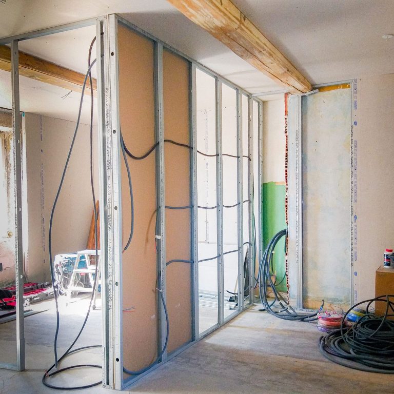 Intérieur d'une pièce en rénovations, avec cloisons en placoplâtre et fils apparents.