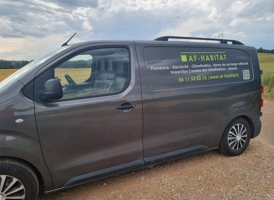 Véhicule utilitaire gris avec un logo affichage AF-HABITAT  de contact sur le côté.