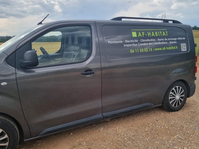 Véhicule utilitaire gris avec un logo affichage AF-HABITAT  de contact sur le côté.