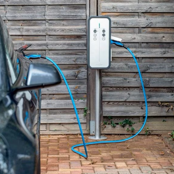 Borne de recharge pour voiture électrique à côté d'un véhicule garé.