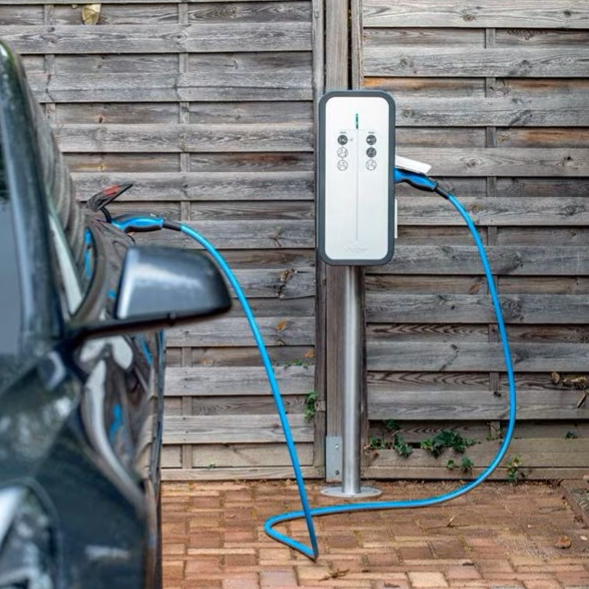 Borne de recharge pour voiture électrique à côté d'un véhicule garé.