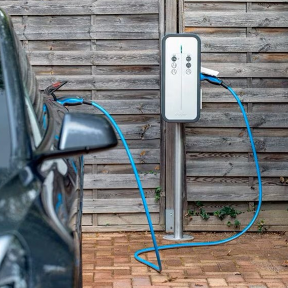 Borne de recharge pour voiture électrique à côté d'un véhicule garé.