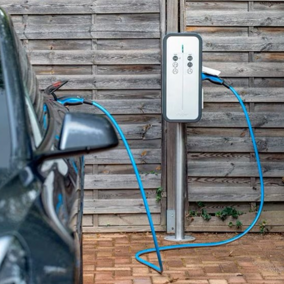 Borne de recharge pour voiture électrique à côté d'un véhicule garé.
