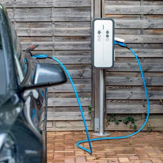 Borne de recharge pour voiture électrique à côté d'un véhicule garé.