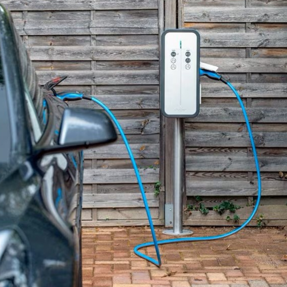 Borne de recharge pour voiture électrique à côté d'un véhicule garé.