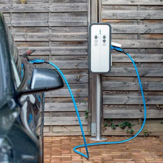 Borne de recharge pour voiture électrique à côté d'un véhicule garé.