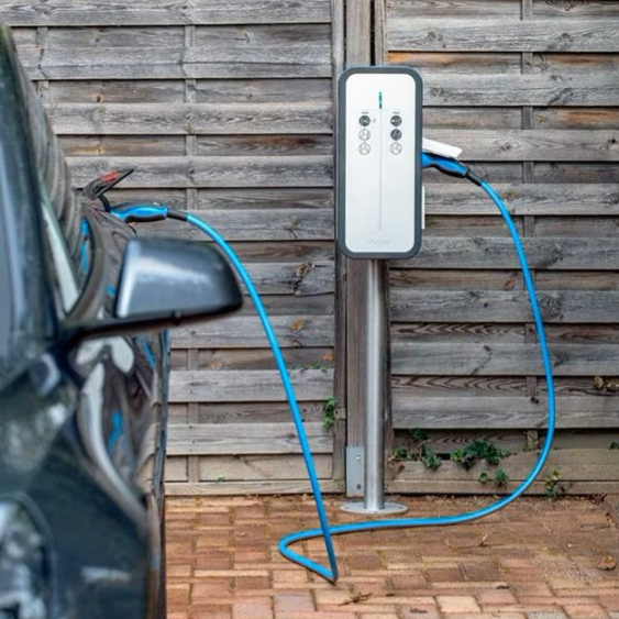 Borne de recharge pour voiture électrique à côté d'un véhicule garé.