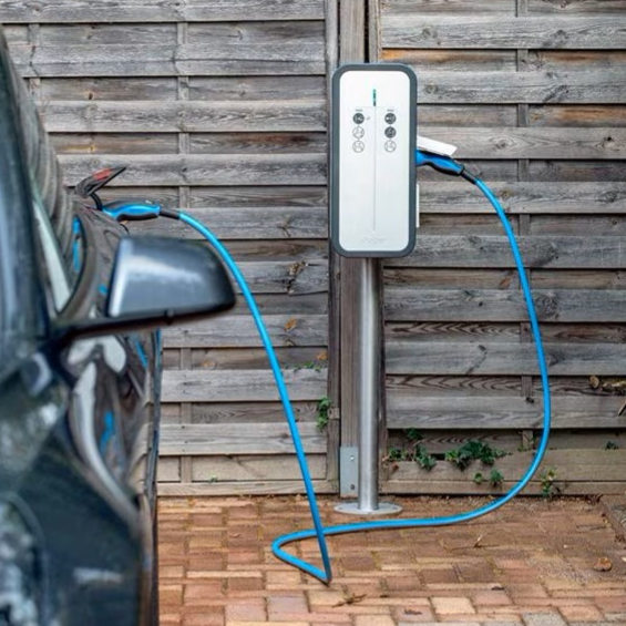 Borne de recharge pour voiture électrique à côté d'un véhicule garé.