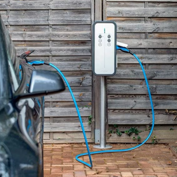 Borne de recharge pour voiture électrique à côté d'un véhicule garé.