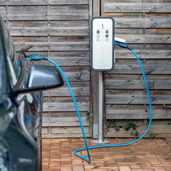 Borne de recharge pour voiture électrique à côté d'un véhicule garé.