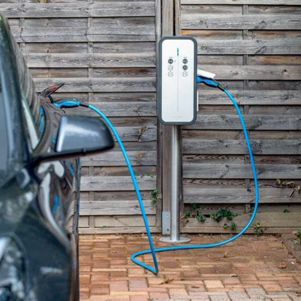 Borne de recharge pour voiture électrique à côté d'un véhicule garé.
