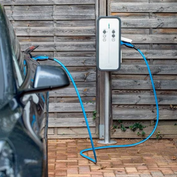 Borne de recharge pour voiture électrique à côté d'un véhicule garé à Heyrieux
